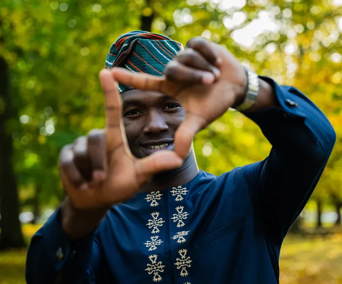 Portrait of a man in a navy embroidered outfit among autumn leaves, photographed by Imisi Bamiro, Coventry photographer