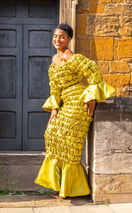 Portrait of a woman in a mustard gown by a church door, photographed by Imisi Bamiro, Coventry photographer