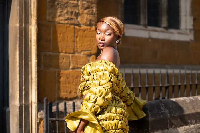Portrait of a woman in a mustard gown by a church door, photographed by Imisi Bamiro, Coventry photographer
